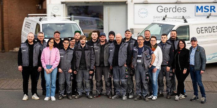Das Team von Gerdes, bestehend aus Männern und Frauen, posiert vor einem weißen Lieferwagen, umgeben von einem freundlichen Ambiente.