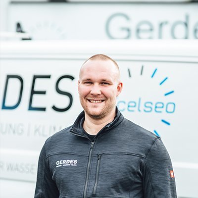 Ein lächelnder Mann steht vor einem Lieferwagen mit dem Logo 'Gerdes', der für Dienstleistungen im Bereich Heizung und Klimaanlage wirbt.